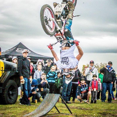 Sam King performs a mini flip on his dirt bike in front of a crowd. 