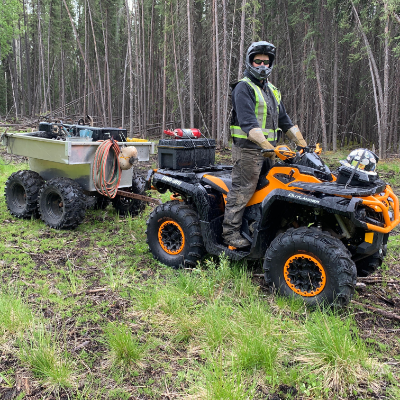 Travis Hallam rides his orange 2016 Can-Am Outlander XTP 1000 in the woods.