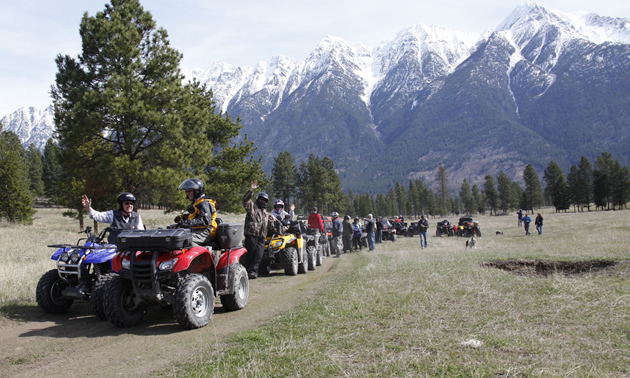 A group of ATVers lined up with mountains in background. 