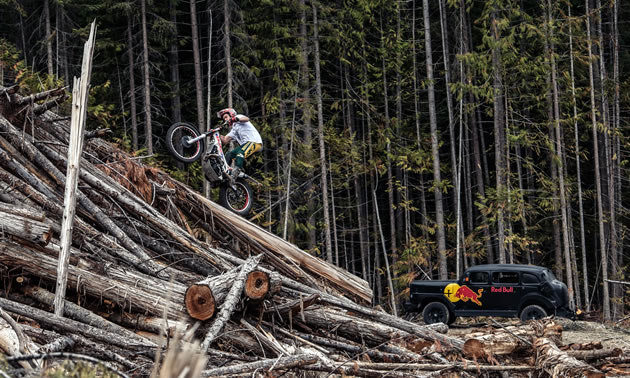 Sam King riding his trials bike on a slash pile. 