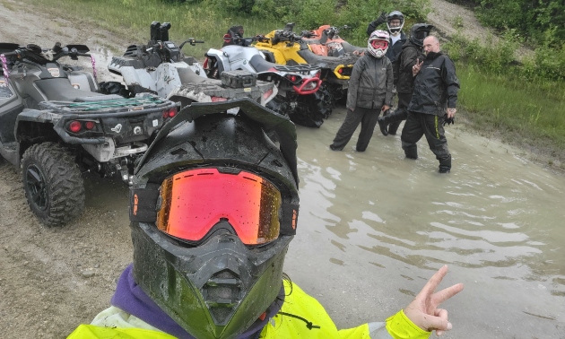 Ema wearing a helmet and giving a peace sign while riding with others