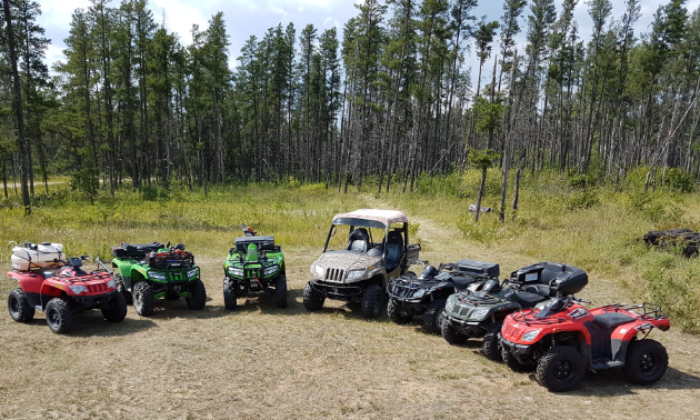 Gary Hora’s family owns a collection of quads, which are lined up in front of a forest.