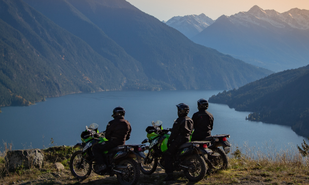 Motorcyclists stop and take in the view of Anderson Lake from up high on a mountain cliff. 