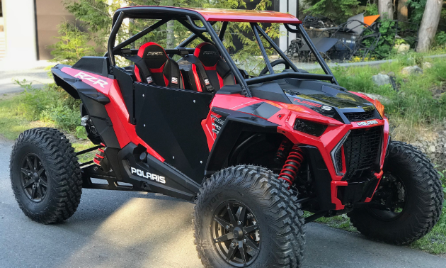A red UTV has a fashionable canopy and roll cage around its frame.