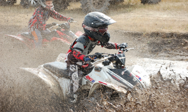 Aiden Lawrence splashes through mud as he powers past a competitor in a race on his ATV