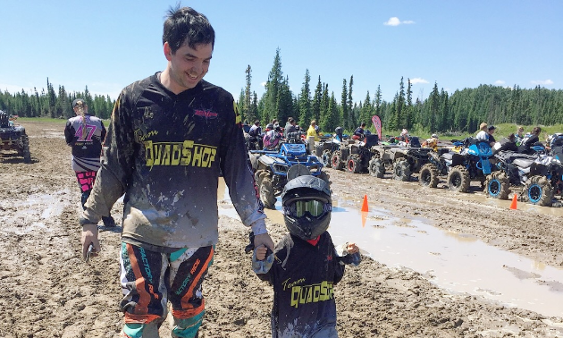 David Lawrence holds his son’s hand as they walk near an ATV race track.