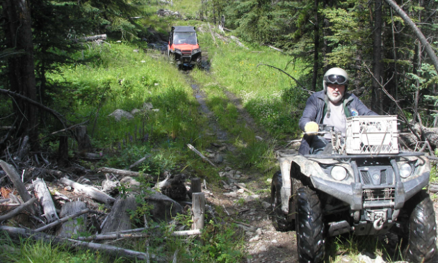 Bob Bogula rides a black ATV on Ridge Trail, followed by an orange UTV in the background.