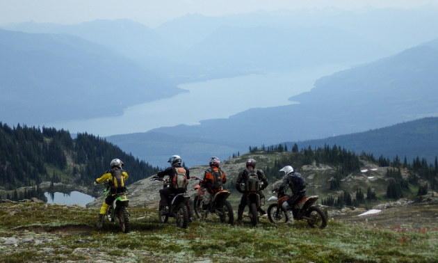 Dirtbikers enjoy the view above Paint Lake with Arrow Lake in the background.