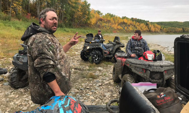 A muddy Chad Taylor gives the peace sign while his friends Matt and Brendan take a break on their ATVs