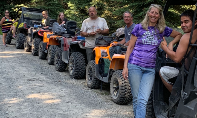 A row of ATVs line up on a trail.