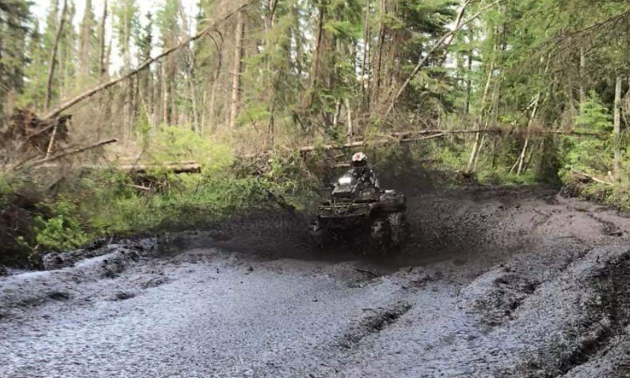 Ryan Ruf plows his ATV through a sludgy road.
