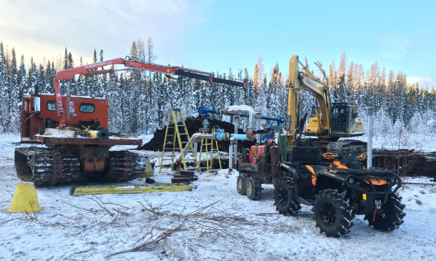 A crane, digger and Travis Hallam’s orange 2016 Can-Am Outlander XTP 1000 are parked at a work site during a pipeline dig-up after a recent snowfall.