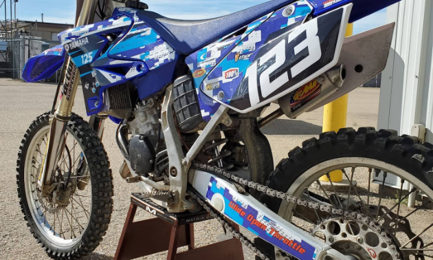 A blue and white dirt bike with camouflage designs.