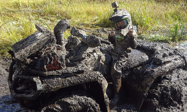 Taigen and his ATV are covered in mud