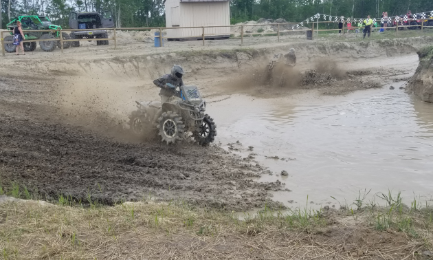 An ATVer rides through a racetrack of mud