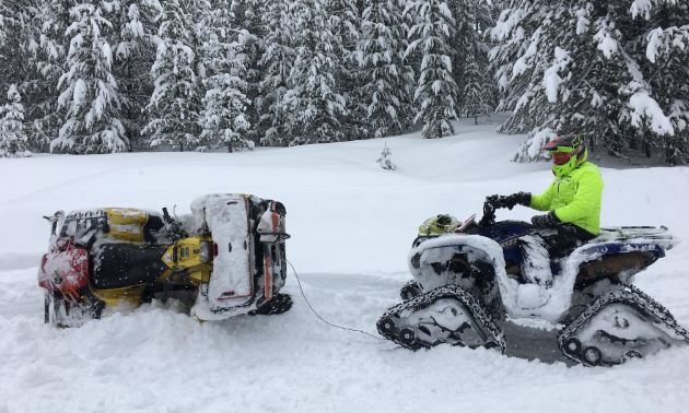 An ATV with treads pulls an ATV that was stuck