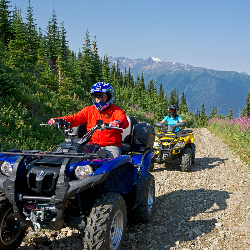 Two ATVers ride a trail in the mountains of British Columbia. 