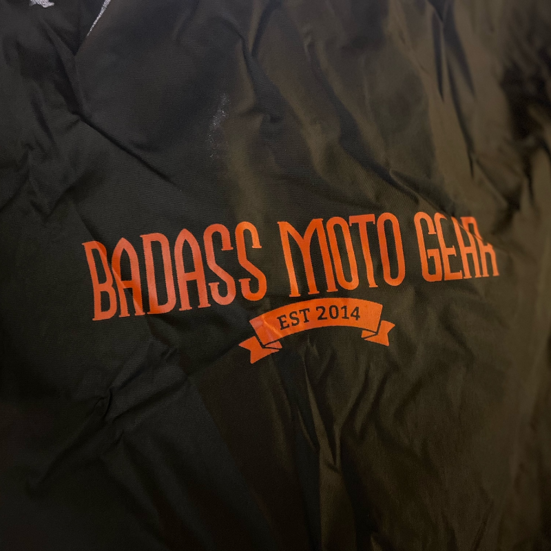 The Badass Moto Gear logo in orange on a black background.