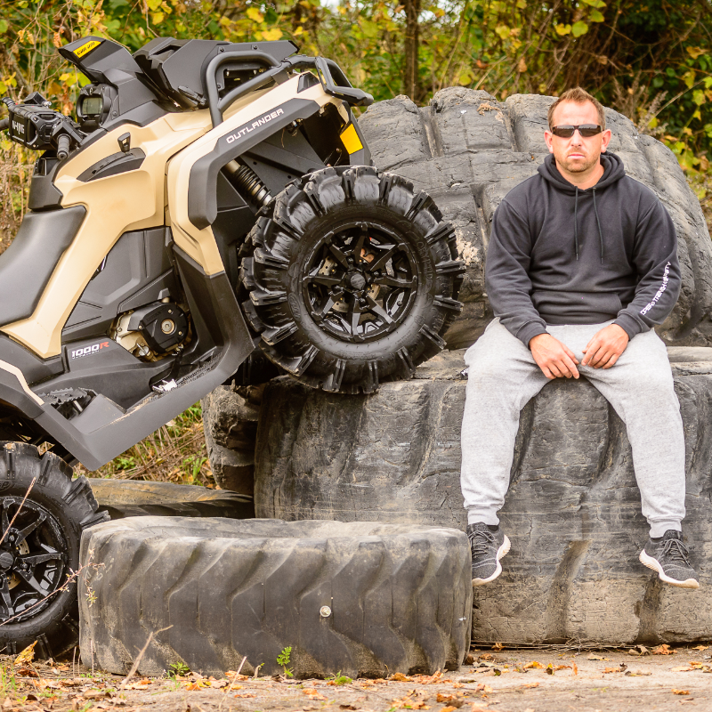 Barrie Martelle sits next to his 2022 Can-Am Outlander XMR 1000 on some giant tires. 