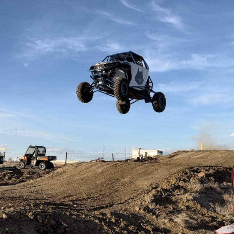 A Polaris RZR gets several metres of air off a big jump on a dirt race track. 