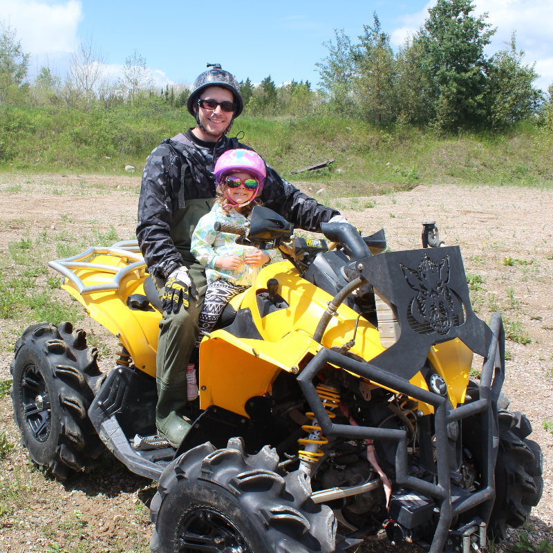 Dan Militere takes his daughter Tess for a ride on a yellow Can-Am ATV. 