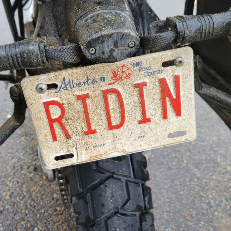 A motorcycle has an Alberta license plate that says Ridin. 