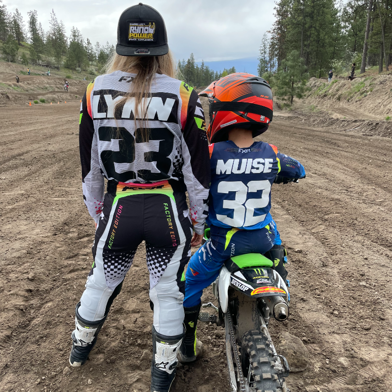Sammi Lynn Clayton stands next to her son, Davian, as he sits on a dirt bike on a track. 