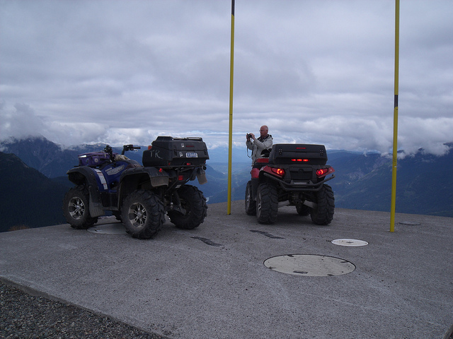 Two quads parked on a platform overlooking a mountain range.