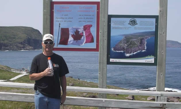 A man standing by a sign at Cape Spear, Newfoundland. 