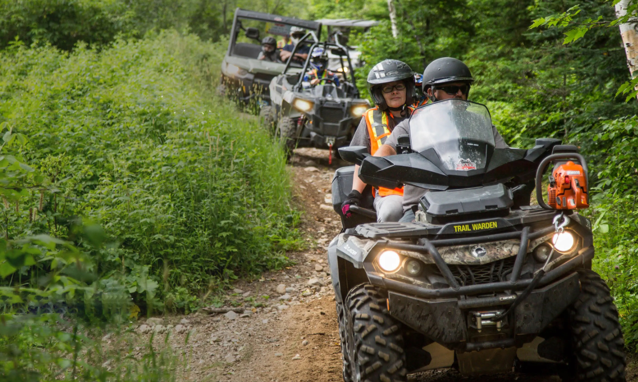 A yellow ATV with a seat attachment on the back. 