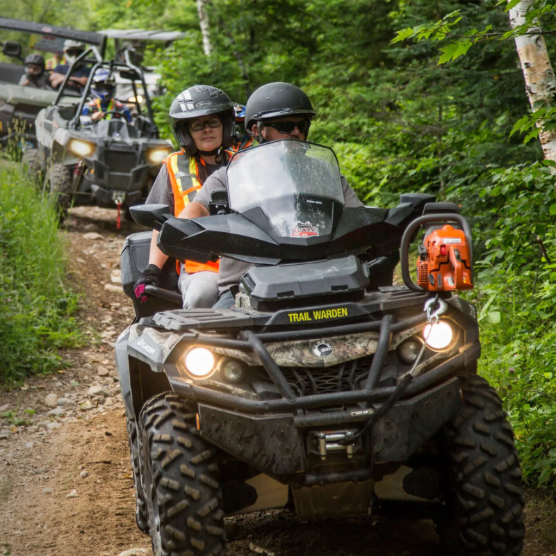 A yellow ATV with a seat attachment on the back. 