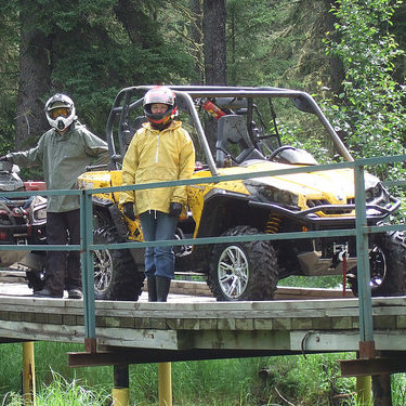 3 quadders stopped on a wooden bridge in the Lakeland Provincial Recreation Area.