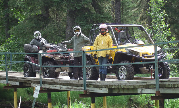3 quadders stopped on a wooden bridge in the Lakeland Provincial Recreation Area.