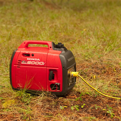 A black and red Honda generator sitting on grass. 