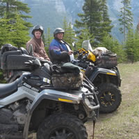 Gordon and his wife sit on a yellow quad against a scenic backdrop.