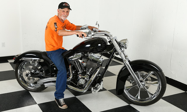 Jerry Wheelz sitting on a black Harley Davidson in the shop. 