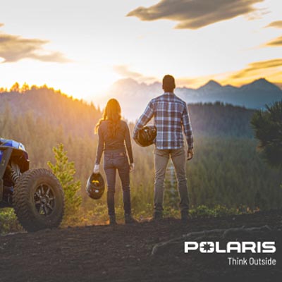 Two people standing side-by-side, looking at sunset, with ATV beside them. 