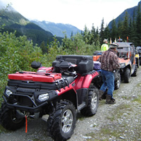 A group of ATVs lined up on a trail. 