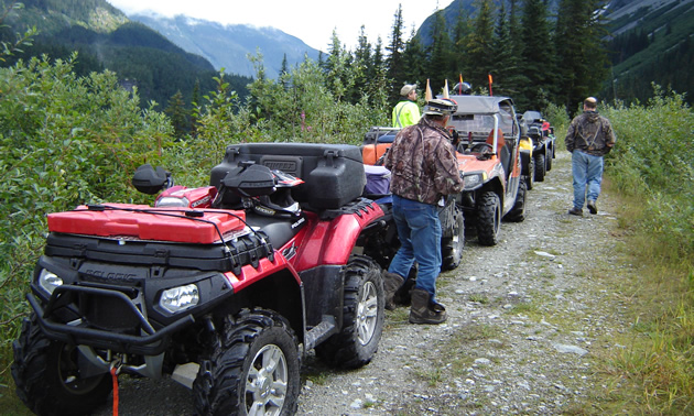 A group of ATVs lined up on a trail. 