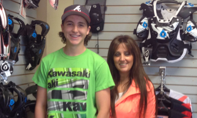 Brayden & Nikki standing next to eachother in a motorcycle shop. 