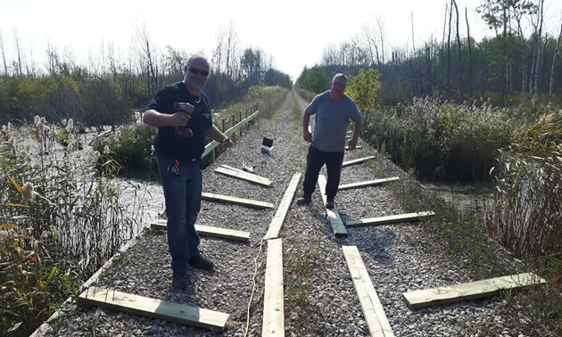 The ATV club members are installing safety railings between the trail and the wetlands.