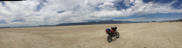 A panorama of the Alvord desert with a dual sport bike in the photo. 