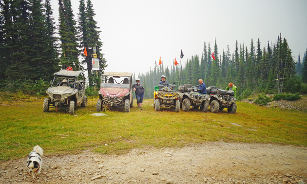 Shown are five ATVs and their riders parked in a field for a break.