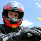 A man wearing a red and black helmet sitting on a yellow bike with the sky in the background. 
