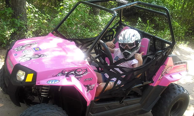 A youth riding a RZR side by side. 
