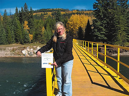 Woman standing on a wooden bridge over a river in the backcountry