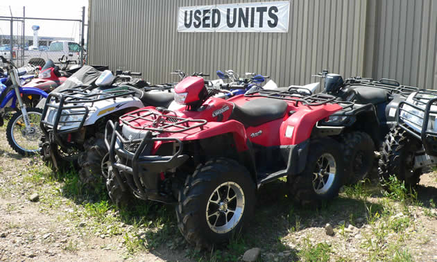 Photo of a red ATV sitting underneath a sign that says Used Units. 