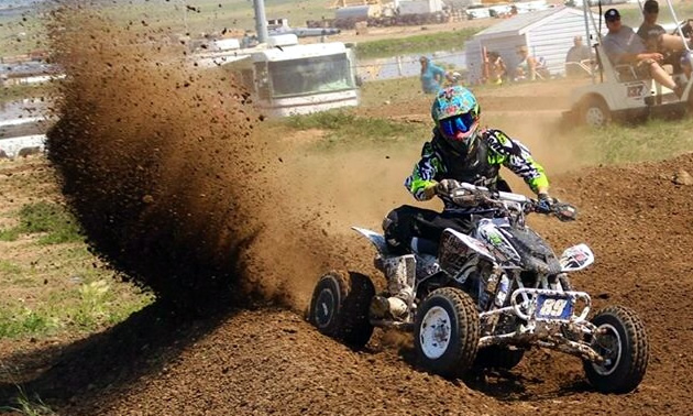 A roost of dirt as an ATV racer comes around the corner. 