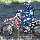 Photo of two people riding dirt bikes on a dirt track. 