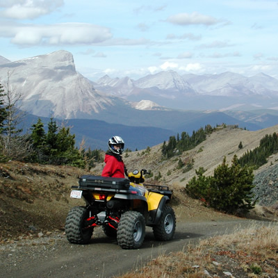 Riders come from near and far to experience the amazing beauty of Southern Alberta's backcountry. Shown is an ATVer parked with the Rocky Mountains in the background.